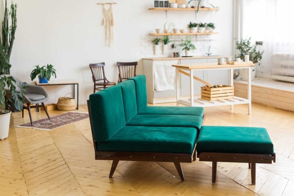 Stylish home interior with green sofa and scandinavian style kitchen on background. Brown wooden
